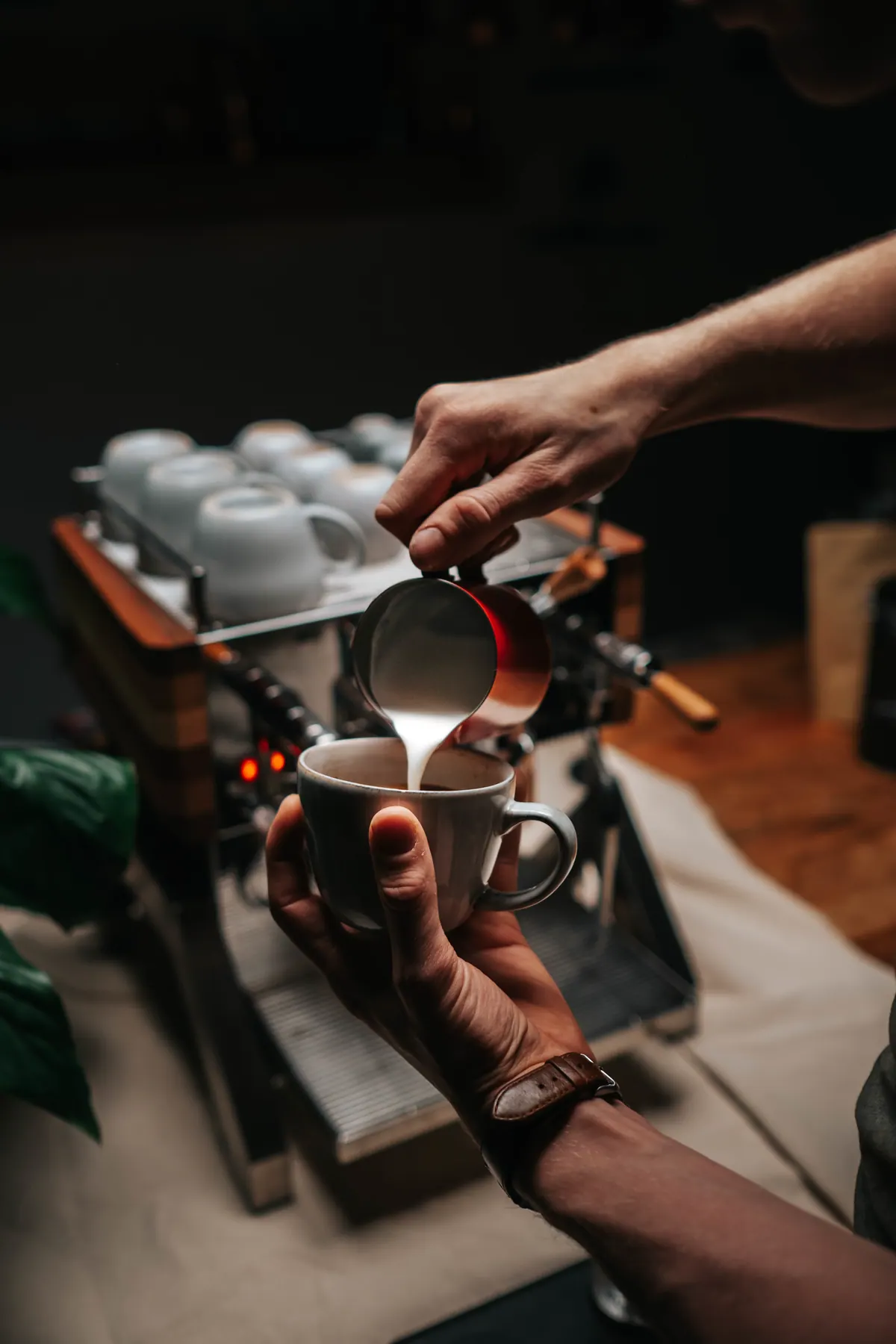Barista gießt Milch in eine Tasse