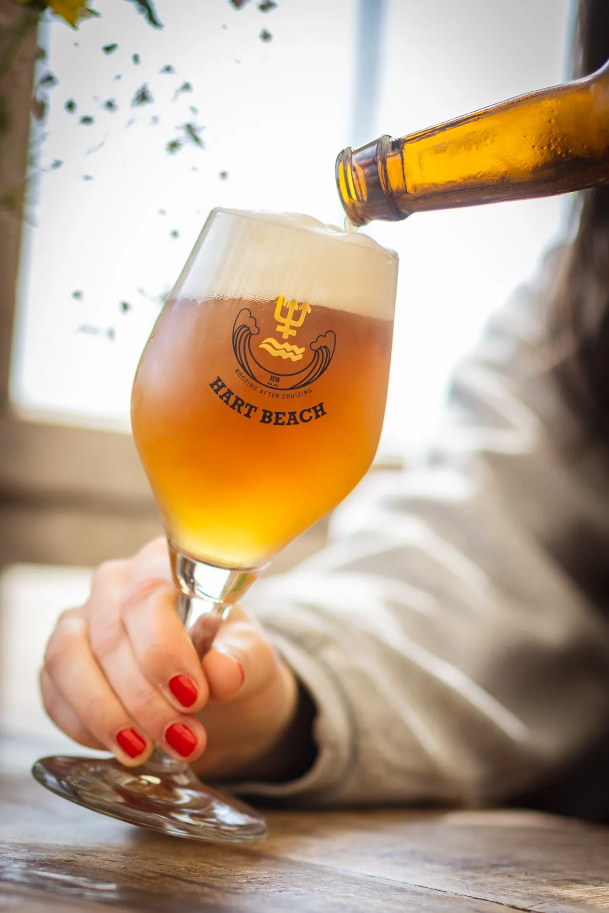 Bier wird in ein Glas mit Hart-Beach-Logo geschenkt
