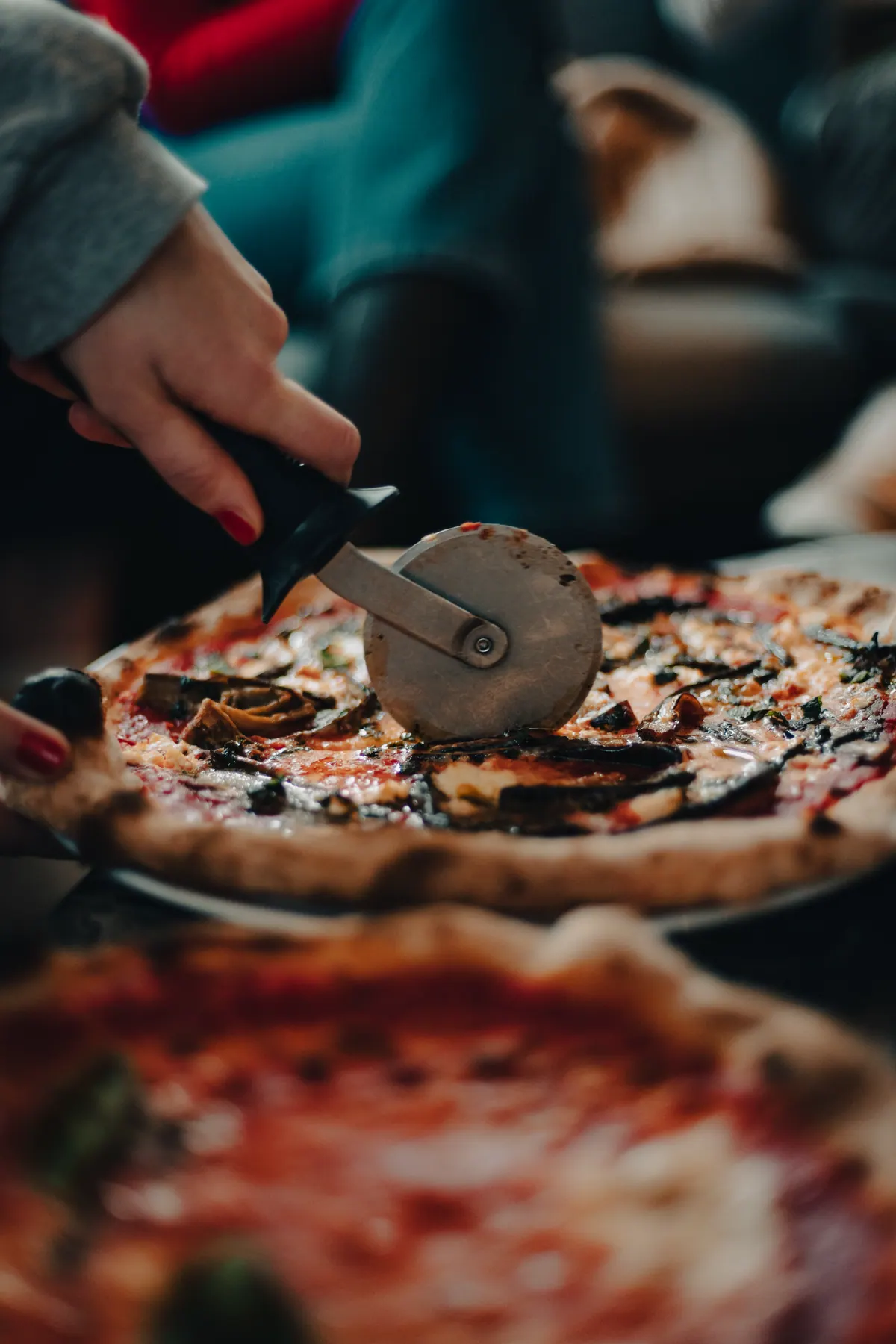 Pizza wird mit dem Rollschneider geteilt