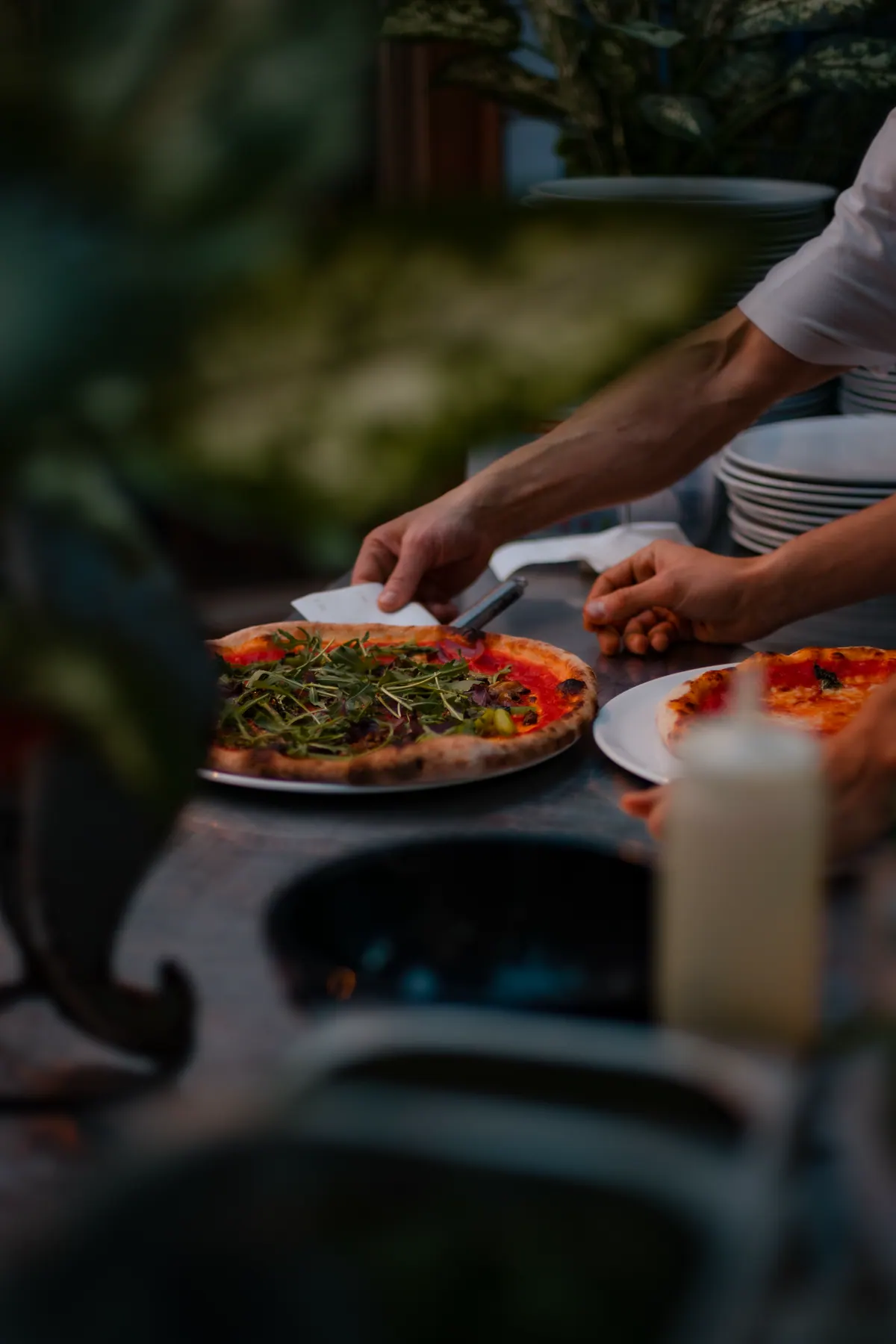 Pizza wird am gedeckten Tisch angerichtet